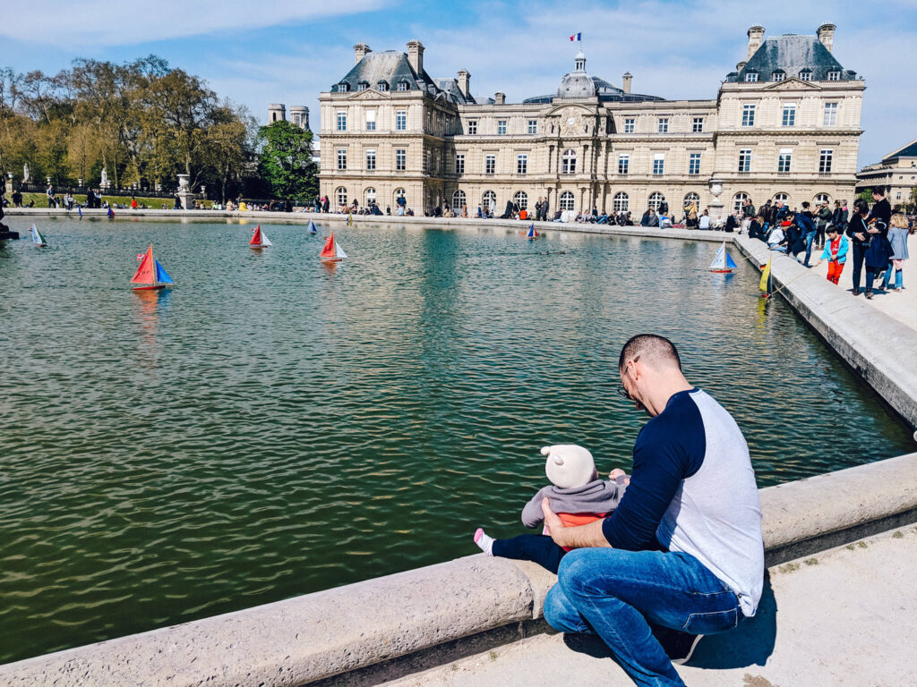 A father holding is little one by the pond in front of the Luxembourg Palace, at the Luxembourg Garden in Paris, France. The Luxembourg Garden is the perfect place to let the kids run and have fun.