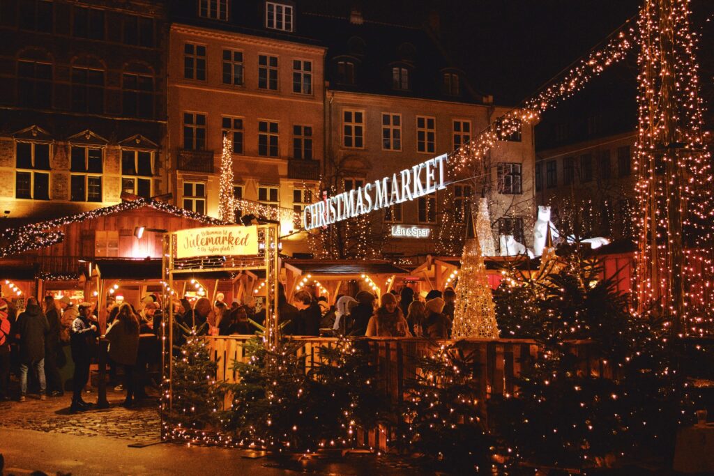 A crowd visiting lit up kiosks at night at one of the best European Christmas markets for kids in Copenhagen.