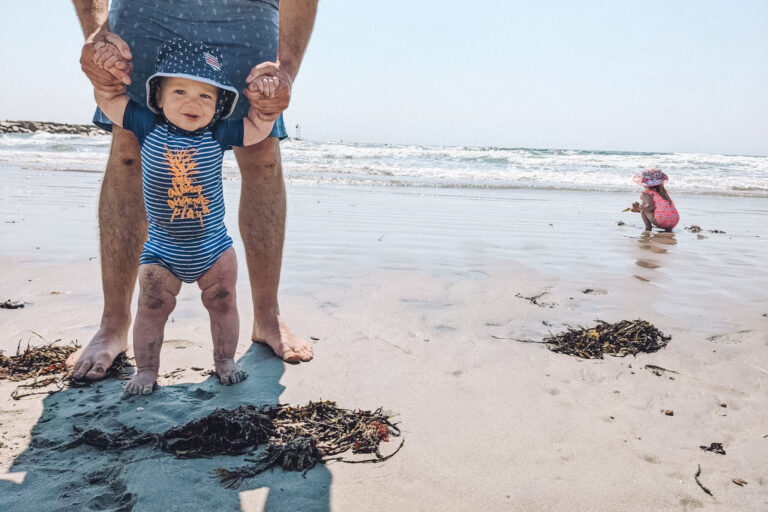 Taking a baby to the beach - baby beach essentials - baby beach gear you should pack - Pictured: a baby and a toddler having fun at one of the best beaches for families in Maines (Wells Beach)