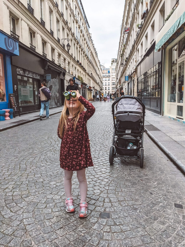Les jumelles sont l'un des meilleurs cadeaux pour les enfants qui aiment voyager! Sur la photo: un enfant à Paris