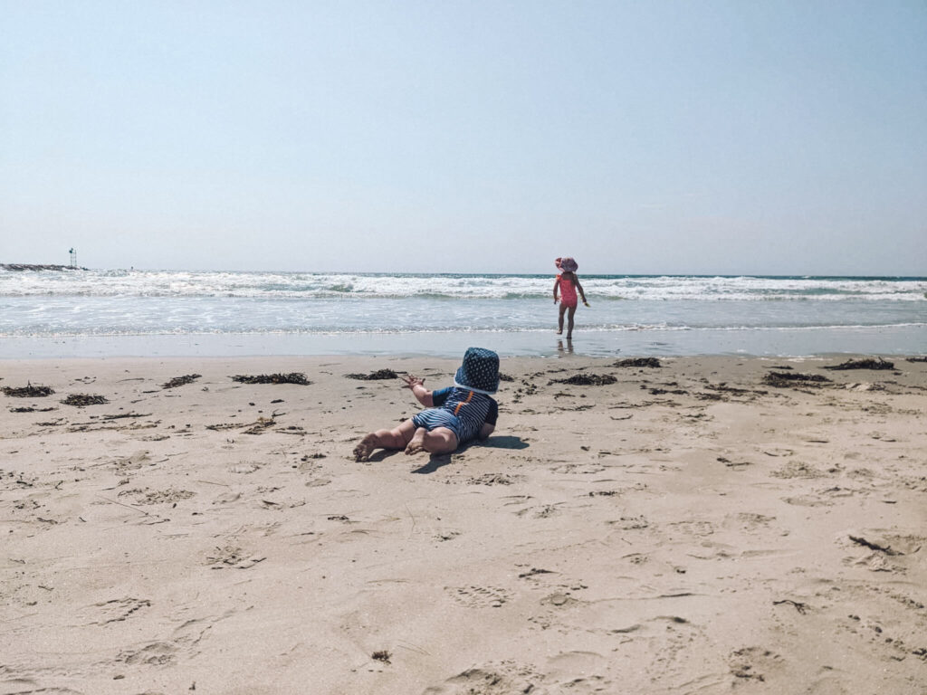 Taking a baby to the beach - baby beach essentials (pictured: a toddler and a baby having fun in one of the best beaches in Maines for families - Wells Beach)