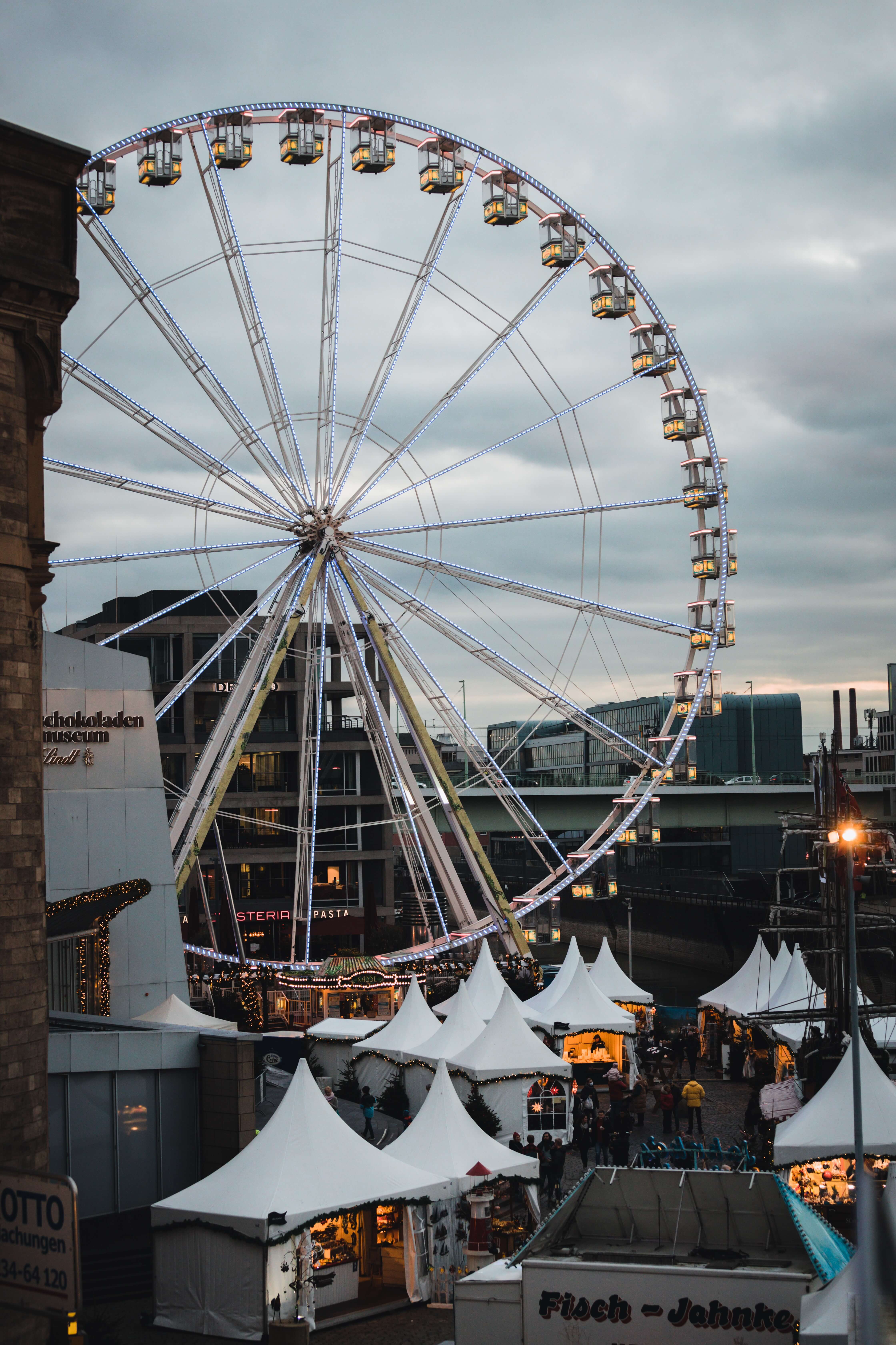 A Ferris Wheel above white stands at one of the best Christmas markets in Europe for families in Cologne