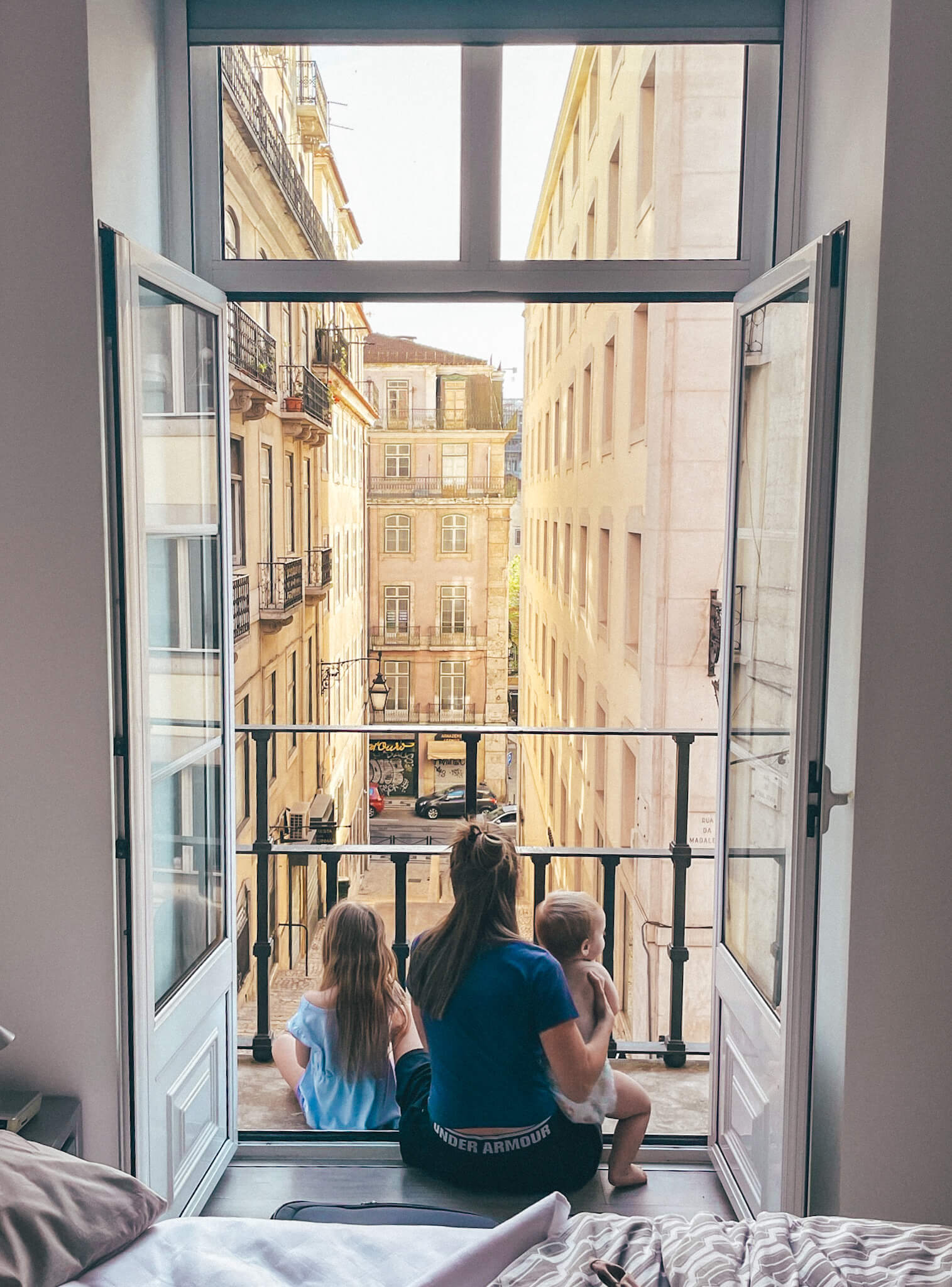 A mother sitting on a balcony with her two kids in Lisbon, Portugal.