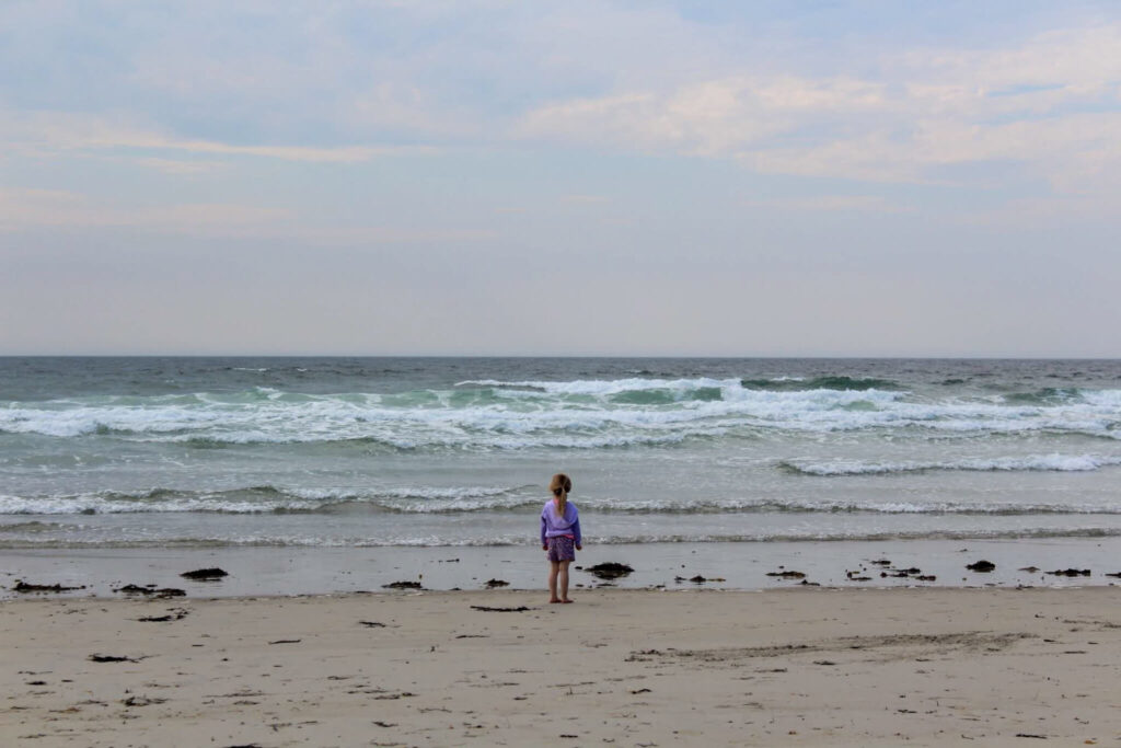 Une toute-petite regarde l'océan à l'une des meilleures plages dans le Maine pour les familles (plage de Wells - Wells Beach)