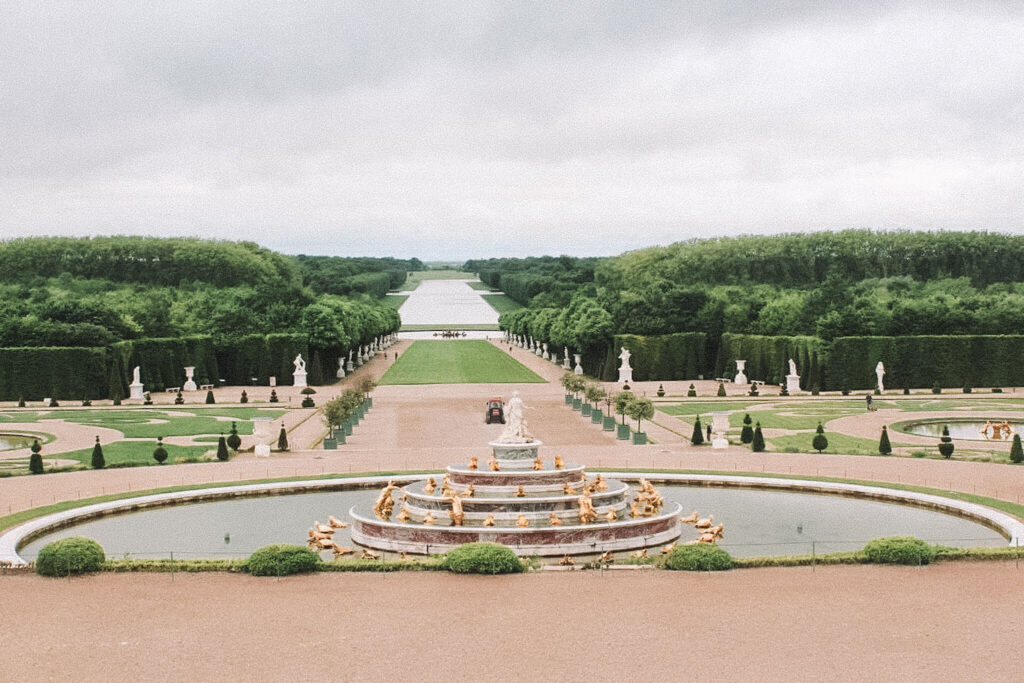 A fountain surrounded by little golden statutes and water in front of the famous gardens of Versailles. It,S a must activity for families in Paris.