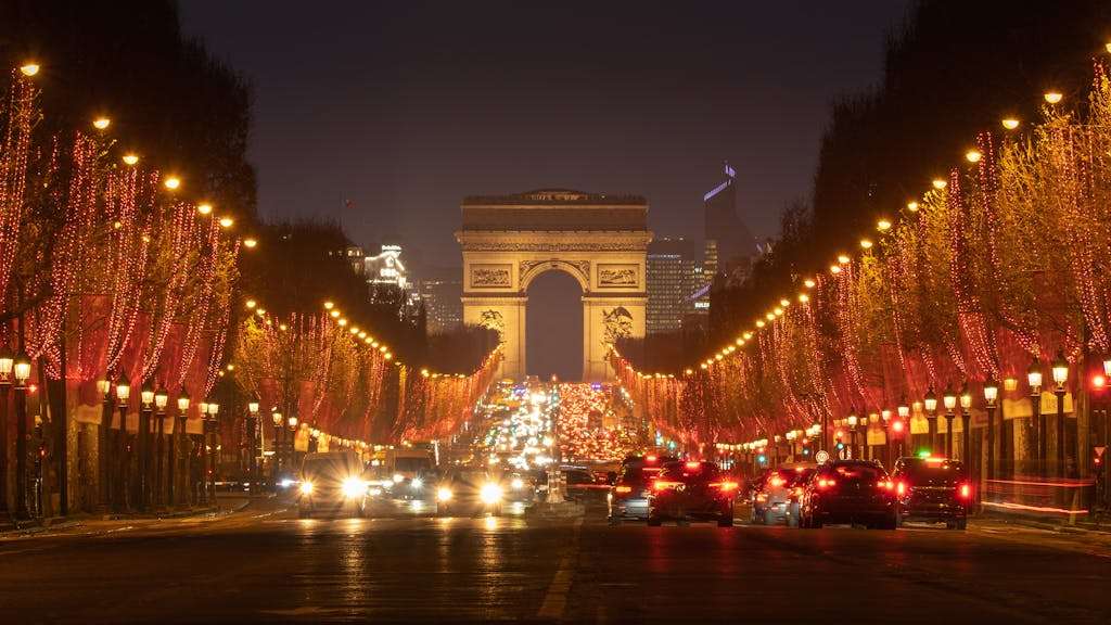 Stunning night view of the illuminated Champs-Élysées in Paris with Arc de Triomphe and festive lights in Paris.