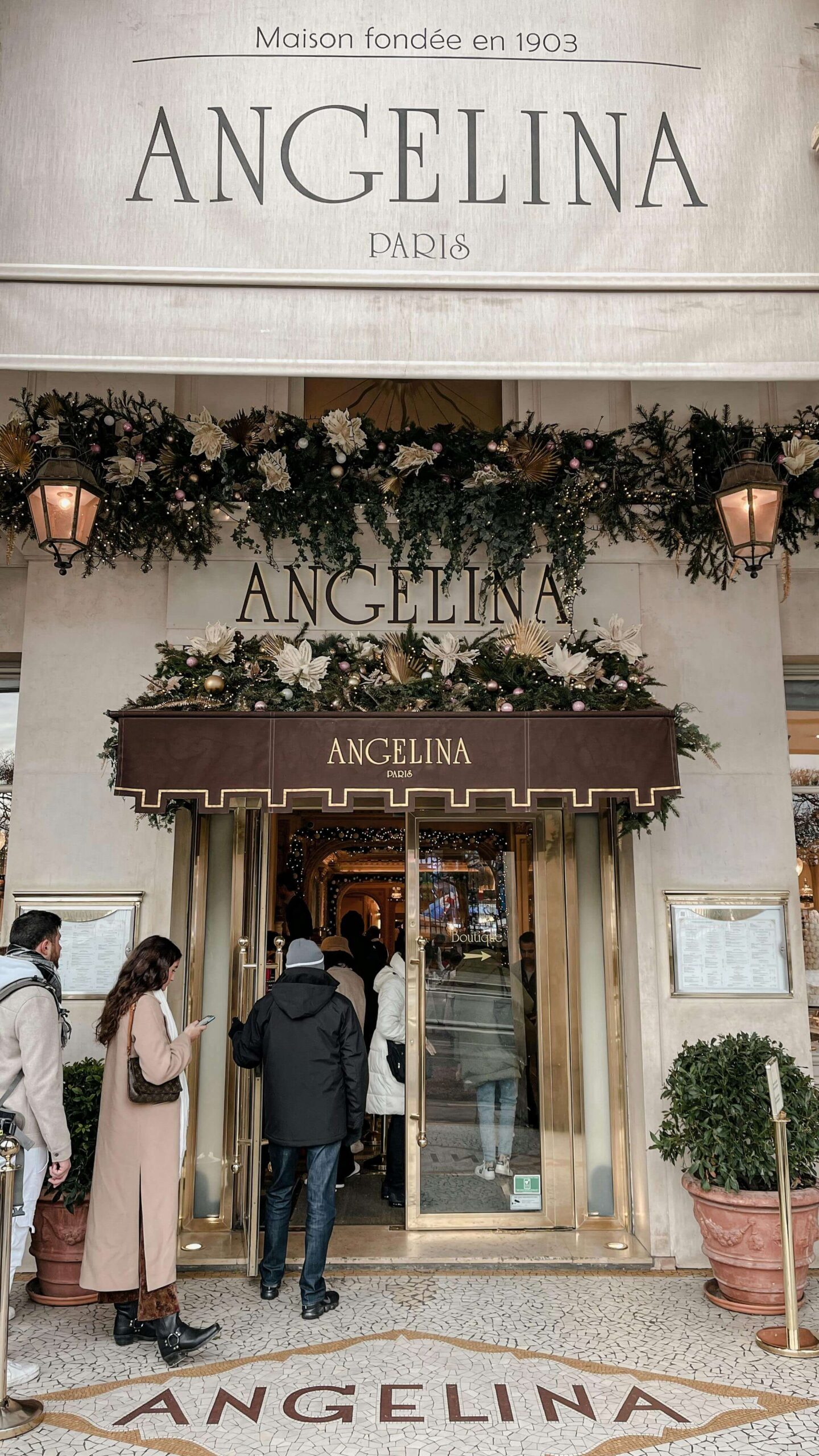 People queuing in front of the door of Angelina Paris, known for serving the most famous hot chocolate in Paris.