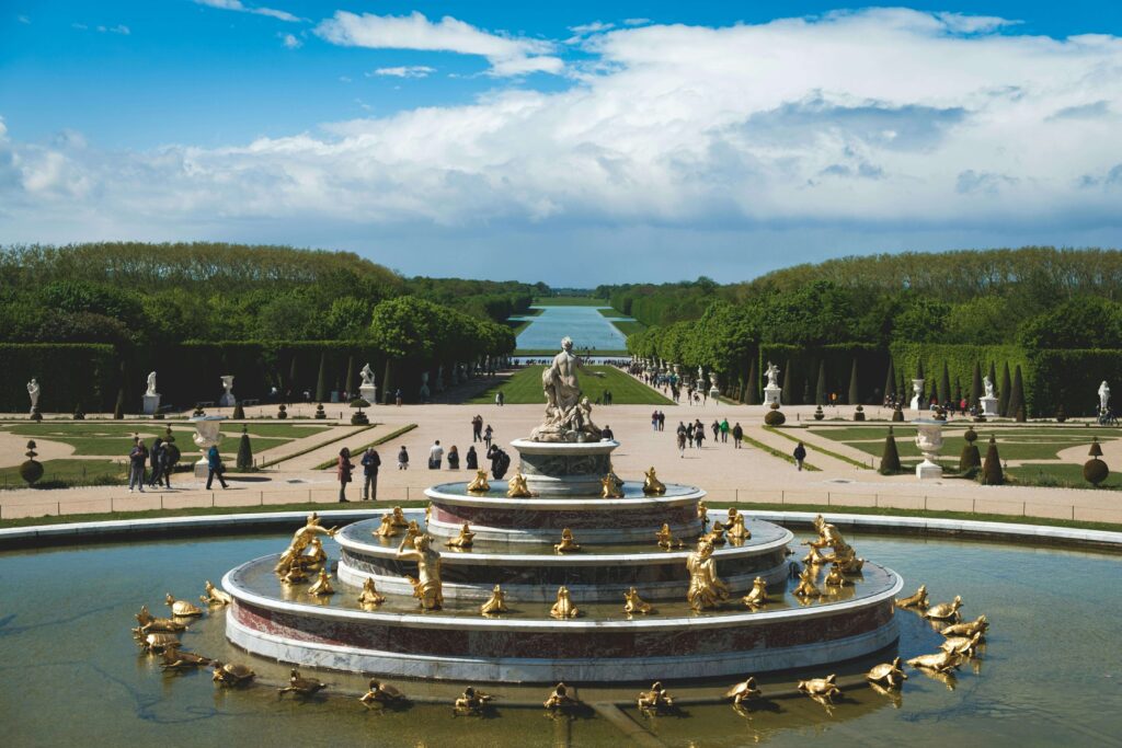 A big fountain surrounded by golden statutes in the Versailles Gardens.