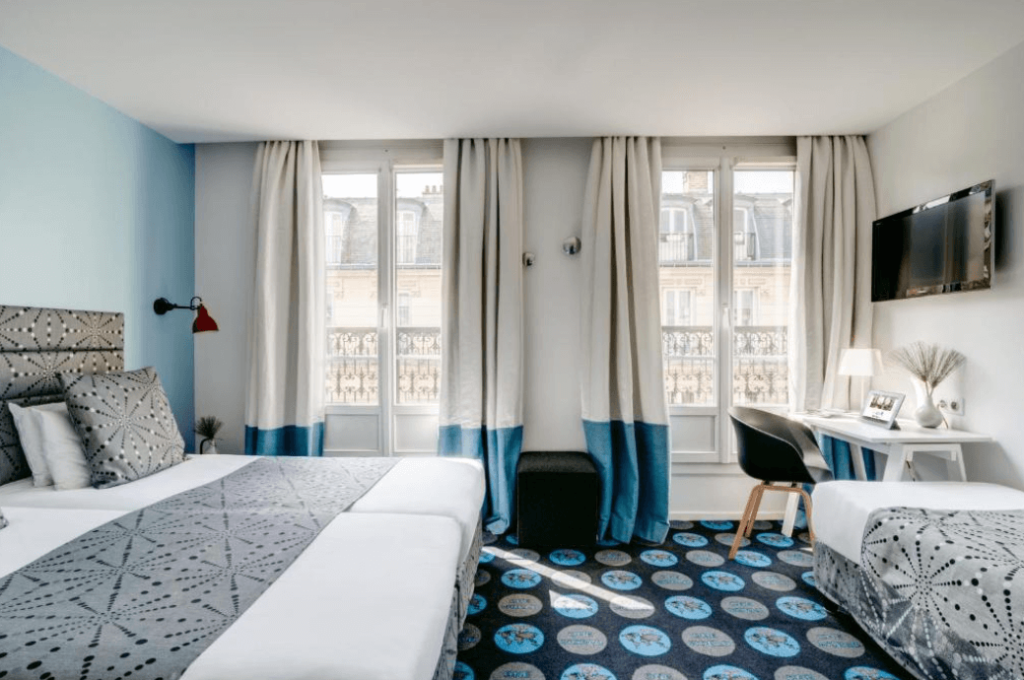 A family room at hotel Astoria by Astotel in Paris, with a double bed on the left side and a twin bed on the right side.
