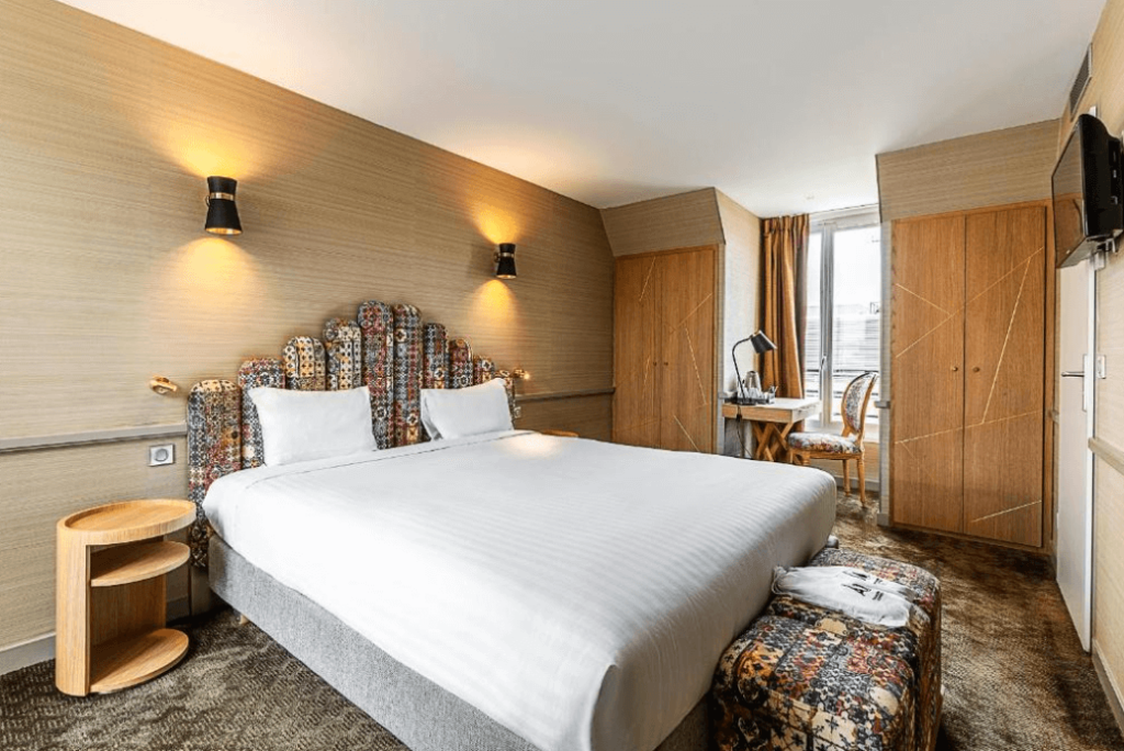 A double bed with white sheets in the middle of the room at Hotel La Manufacture in Paris. 