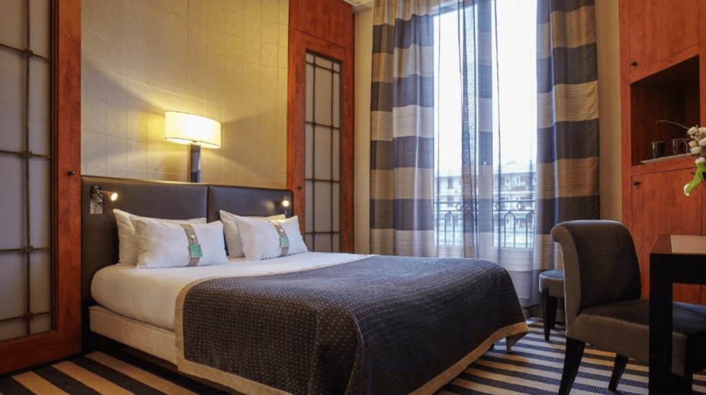 An affordable hotel room for families at the Holiday Inn Gare de Lyon Bastille in Paris featuring a double bed with a dark gray duvet. 