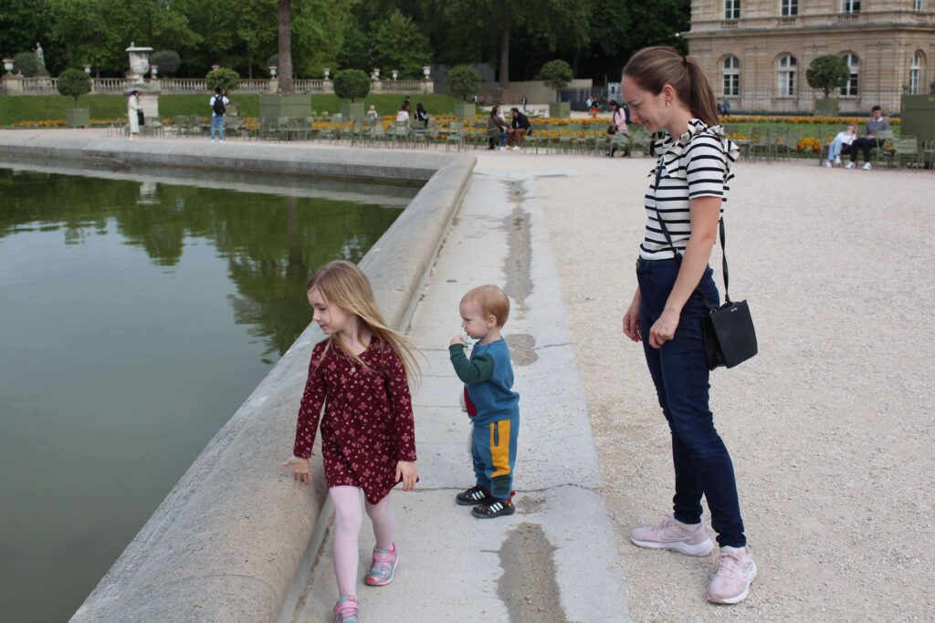 A mother with her two kids looking at the pond in the Luxembourg Garden in Paris. This is a toddler-friendly activity worth adding to a Paris itinerary.