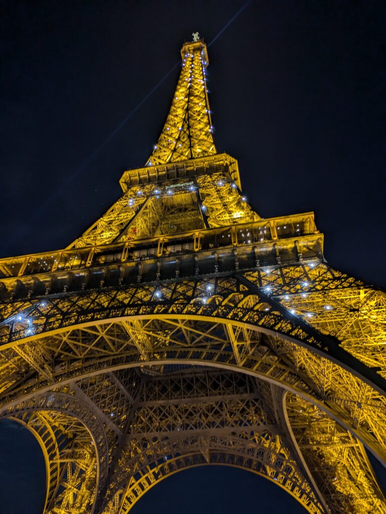 The Eiffel Tower seen from below, sparkling against a pitch black night sky. It's a memorable thing to do in Paris with a toddler.