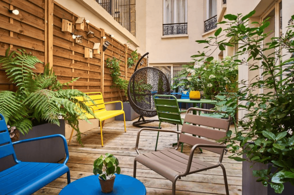 A terrace with a few chairs and a wooden wall at the Hotel Magenta 38 by Happyculture in Paris.