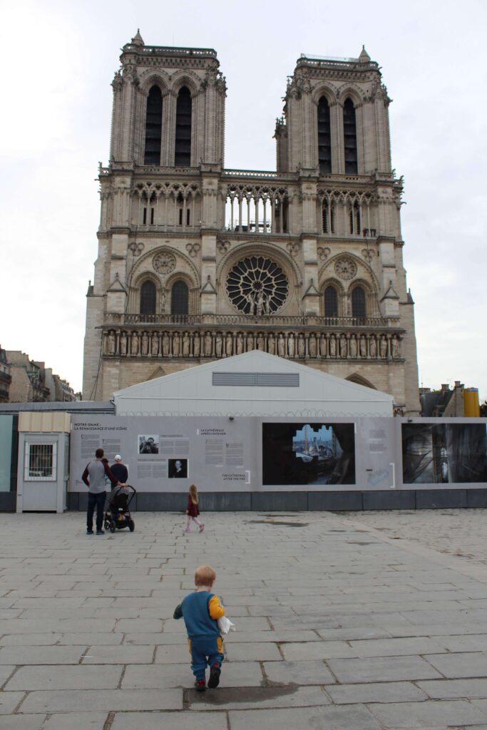 A toddler walking towards Notre-Dame Cathedral in Paris while it was still under construction. It's free for all to visit the Cathedral.