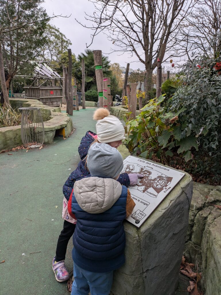 Deux jeunes enfants qui regardent une affiche dans l'aire de jeux Nelson Mandela à Paris.