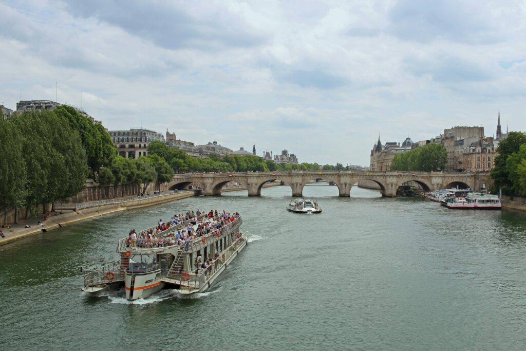 A boat cruising on the Seine in Paris, France, on a cloudy day. If you're spending only one day in Paris, a cruise on the Seine is the best way to see as many Paris attractions and landmarks as possible.