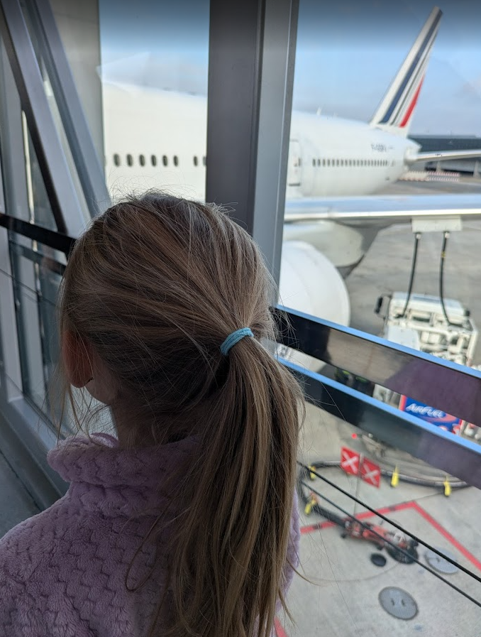 Girl with a light purple vest and a dark blond ponytail boarding an Air France plane at CDG airport in Paris.