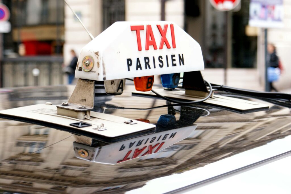 Taxi Parisien sign on top of a cab's roof in Paris. Taxis are the easiest way to go to Paris from CDG with kids.