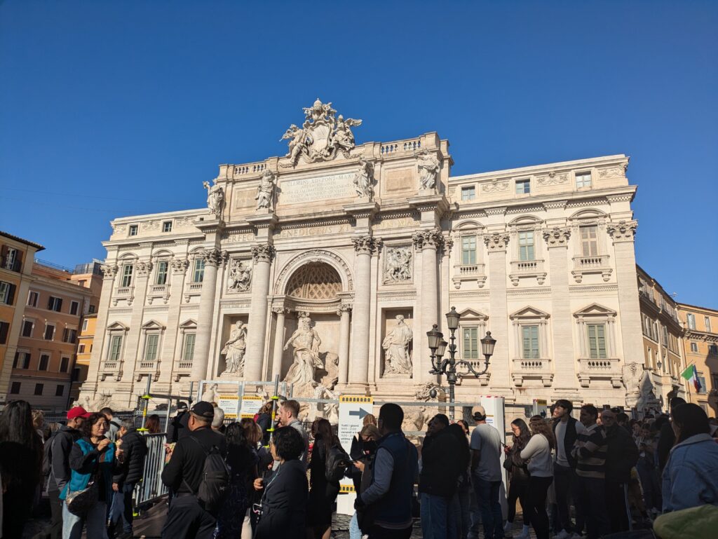 Crowds in front of the Trevi Fountain undergoing renovations in Rome, Italy. If it's on your Rome itinerary with kids, make sure to head to the Fountain early.