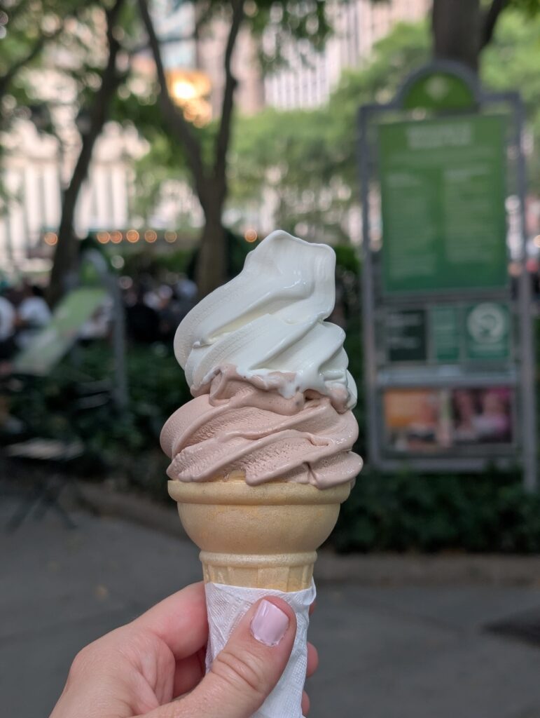 A woman's hand holding an ice cream cone at Bryant Park in NYC.