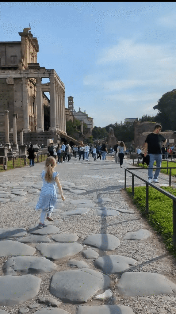 Little girl running on a stone path at the Roman Forum on a sunny day in Rome, Italy