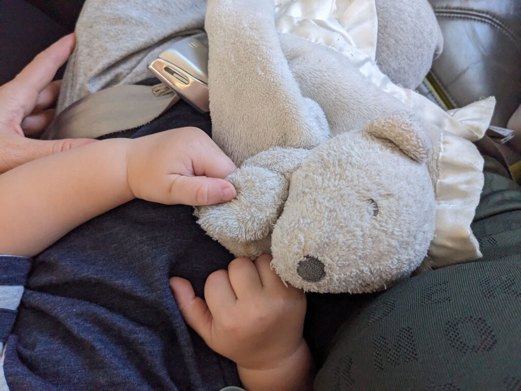 A toddler holding a white plush toy on a plane.
