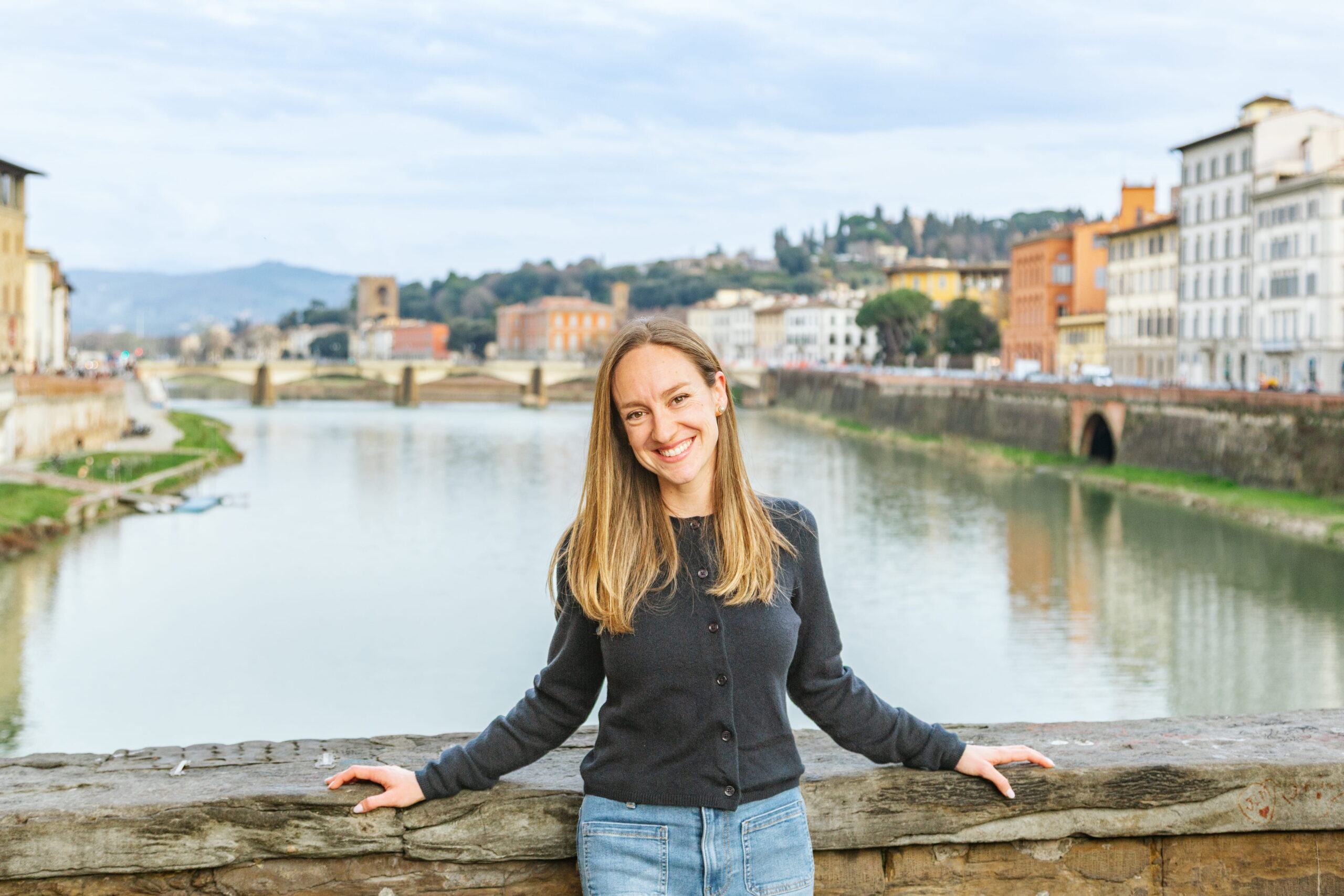 Sophie Graveline, mère de deux jeunes voyageurs et fondatrice de The Family Aboard, est posée souriante sur le Ponte Vecchio à Florence, en Italie.