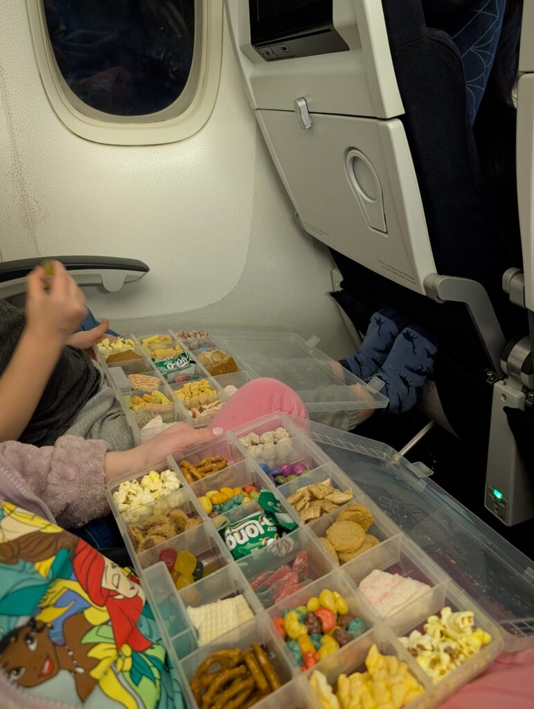 Deux enfants mangent des collations à partir de leur boîte à collation dans l'avion. 