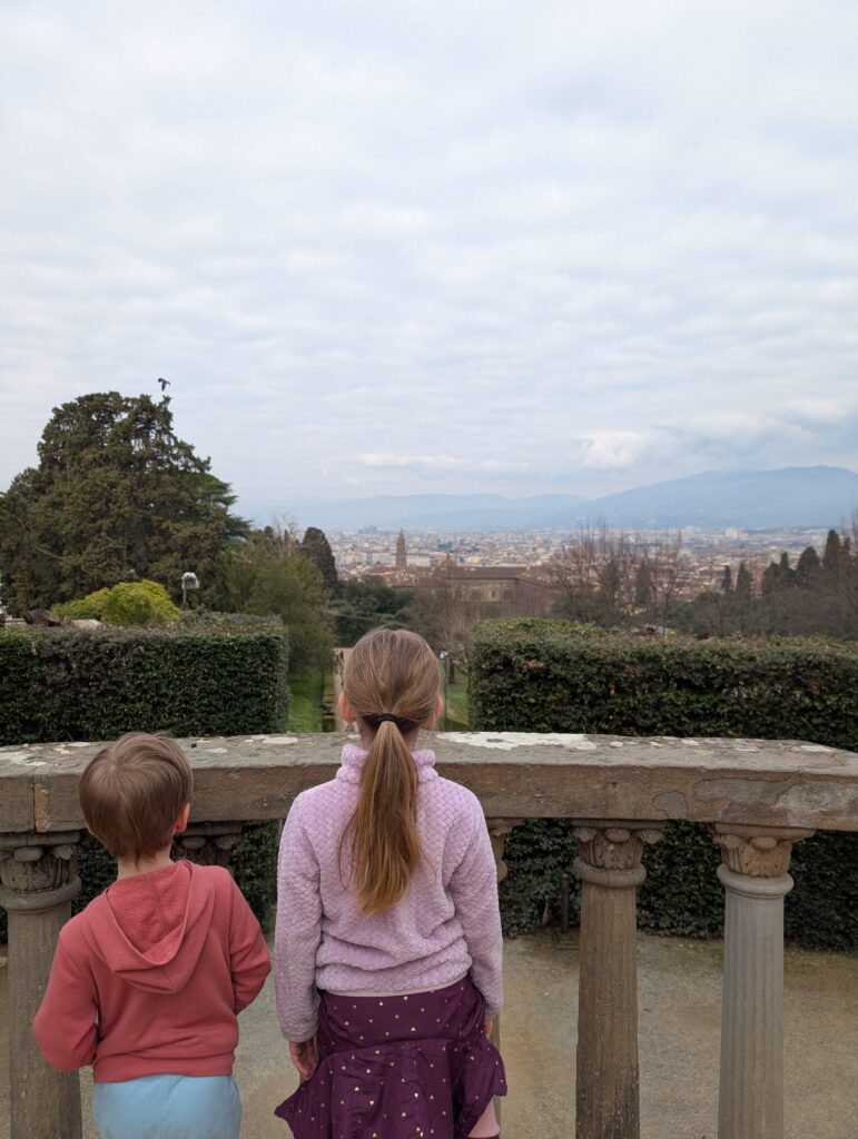 A little boy with his older sister standing on a balcony at Boboli Gardens and looking at the city views in Florence, Italy.