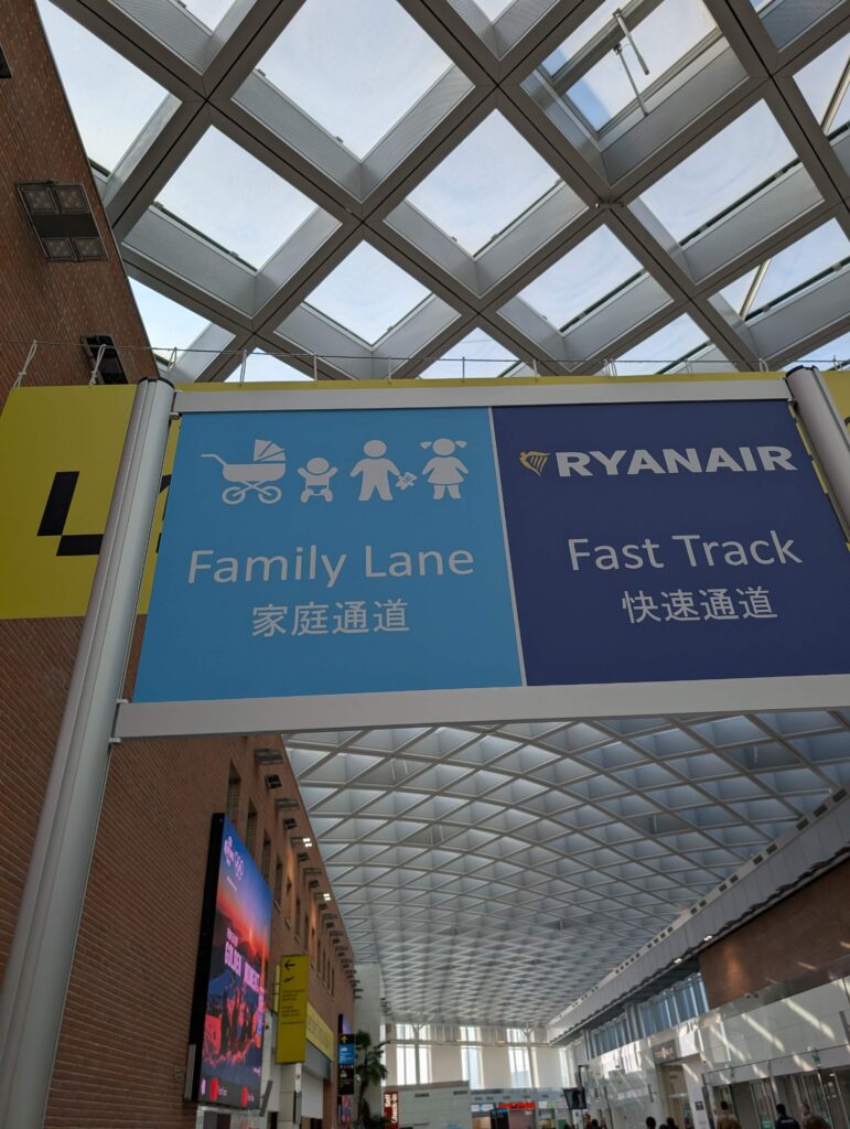 Affiche bleue signalant l'entrée de la ligne prioritaire pour les familles pour passer la sécurité à l'aéroport.