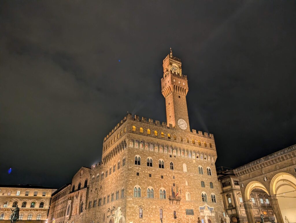 Palazzo Vecchio at the Piazza della Signoria lit up at night in Florence, Italy. Stopping at the Piazza is one of the coolest things to do in Florence with kids. 