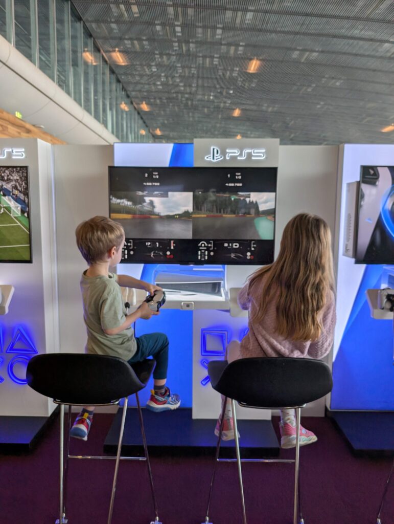 Un tout-petit garçon et une jeune fille s'amusent à une station de PS5 à l'aéroport Paris-Charles de Gaulle. 